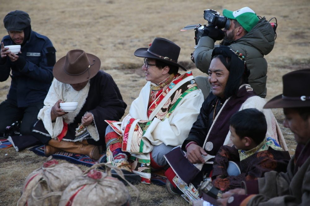 Zadoi, China - Jackie Chan sits with locals while a cameraman films Arthur eating the food provided.